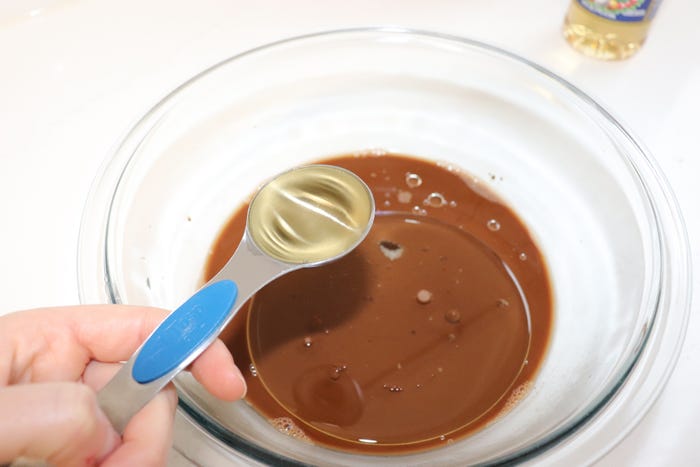 A tablespoon of apple cider vinegar pours into cake mix.